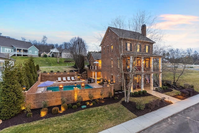 exterior space featuring a patio, a yard, a chimney, and a balcony