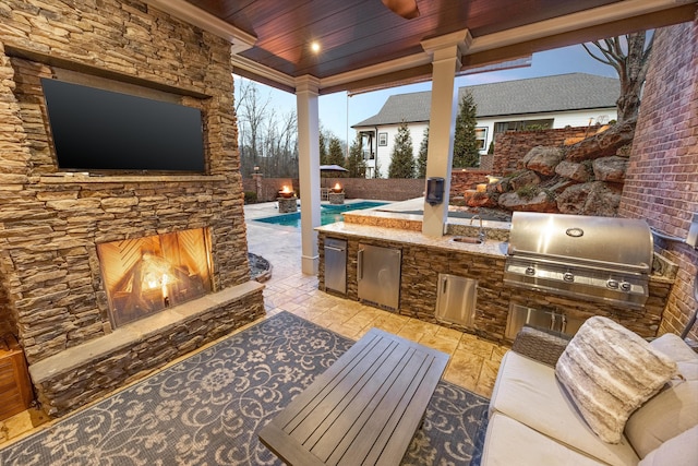 view of patio with an outdoor stone fireplace, exterior kitchen, and area for grilling