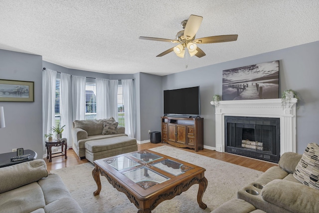 living room with ceiling fan, a textured ceiling, and light hardwood / wood-style flooring