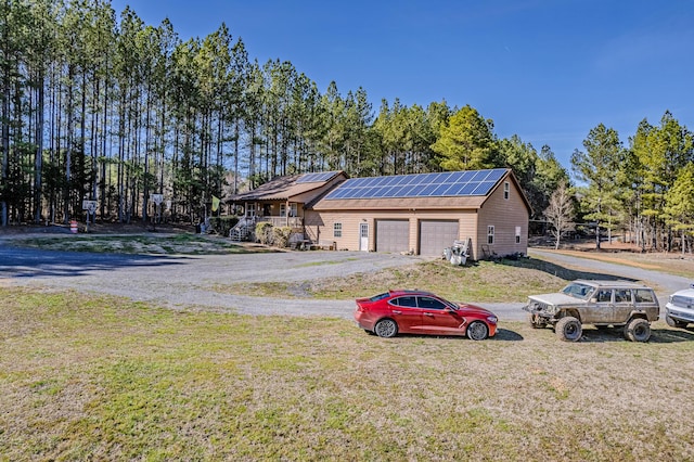 view of front of property with a garage, roof mounted solar panels, and a front lawn