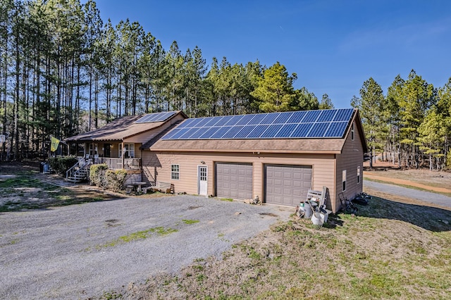 exterior space featuring aphalt driveway, roof mounted solar panels, and roof with shingles