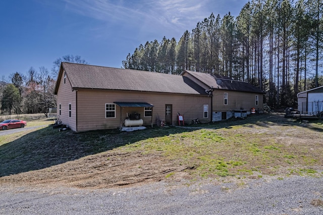 view of property exterior featuring roof with shingles and a lawn