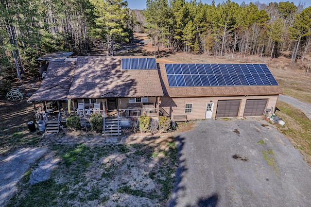 view of front of home with roof with shingles, a gambrel roof, roof mounted solar panels, a garage, and driveway