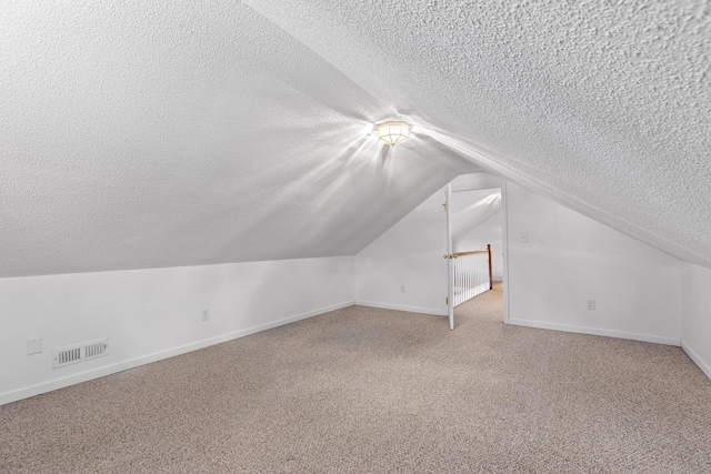 additional living space featuring carpet floors, a textured ceiling, and lofted ceiling