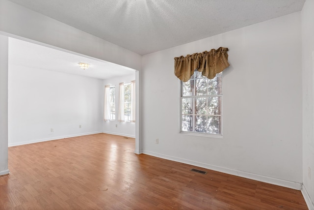 unfurnished room with plenty of natural light, wood-type flooring, and a textured ceiling