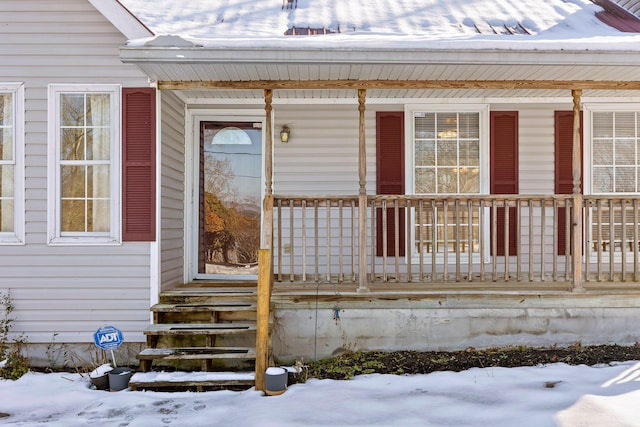 snow covered property entrance with covered porch