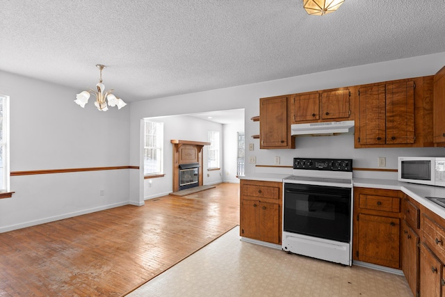 kitchen featuring decorative light fixtures, a notable chandelier, electric range oven, and a textured ceiling