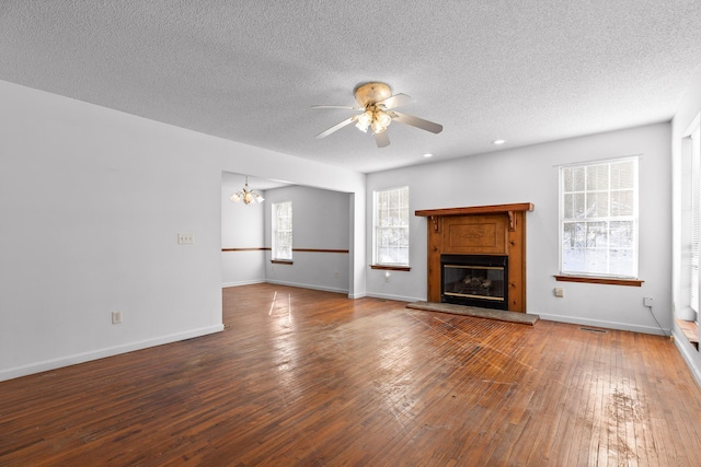 unfurnished living room with a textured ceiling, ceiling fan with notable chandelier, and hardwood / wood-style floors