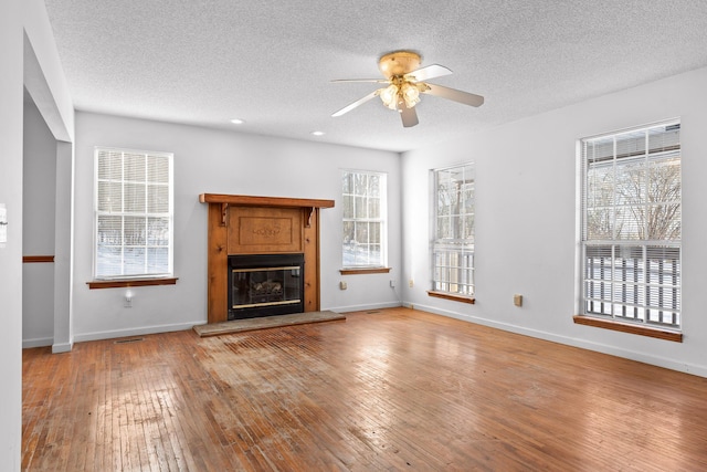 unfurnished living room with ceiling fan, a textured ceiling, and light hardwood / wood-style flooring