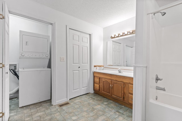 bathroom with stacked washing maching and dryer, a textured ceiling, vanity, and shower / bathing tub combination