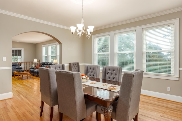 dining space with an inviting chandelier, ornamental molding, and light hardwood / wood-style flooring