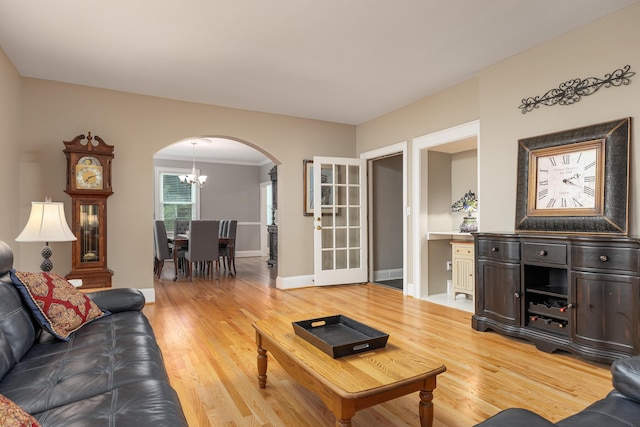 living room featuring an inviting chandelier, crown molding, and light hardwood / wood-style flooring