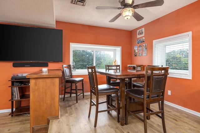 dining space featuring a textured ceiling, ceiling fan, and light wood-type flooring