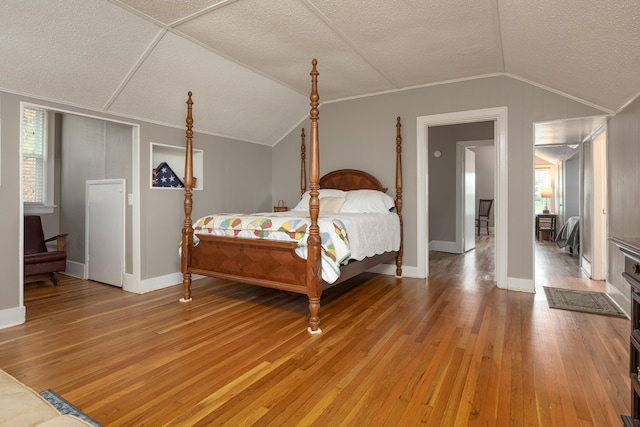 bedroom featuring ornamental molding, lofted ceiling, wood-type flooring, and a textured ceiling