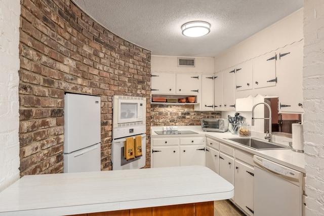 kitchen with white cabinetry, sink, white appliances, and kitchen peninsula