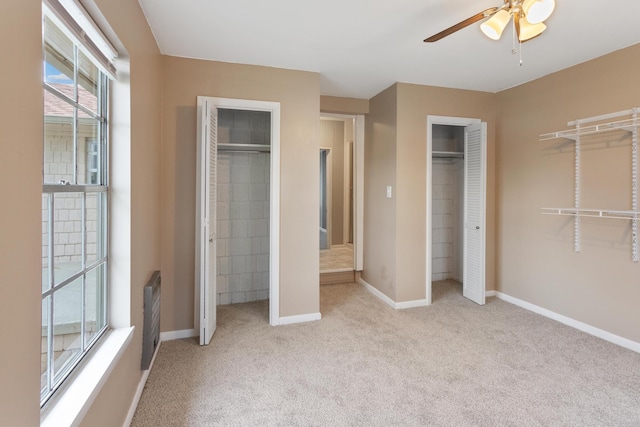 unfurnished bedroom featuring light carpet, two closets, and ceiling fan