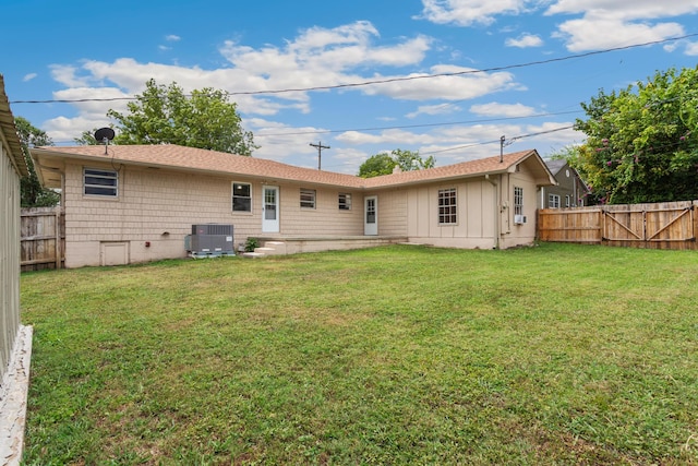 back of property with a lawn and central air condition unit