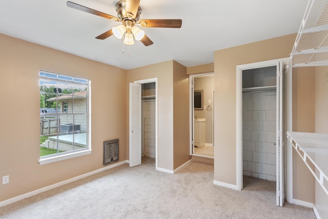 unfurnished bedroom featuring light carpet, two closets, ensuite bath, and ceiling fan