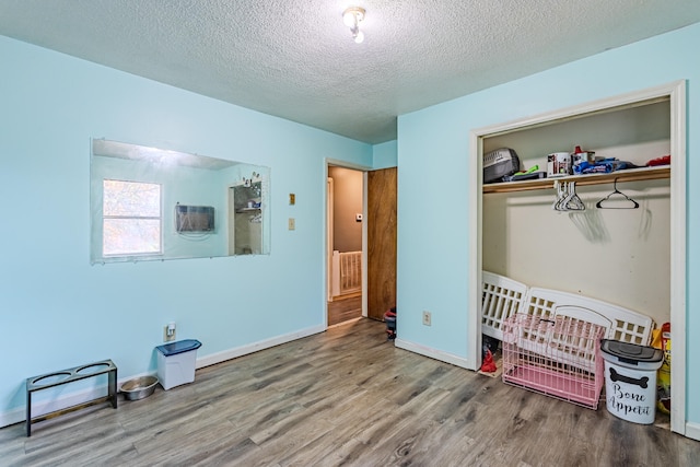 bedroom featuring a textured ceiling, a closet, hardwood / wood-style floors, and a crib