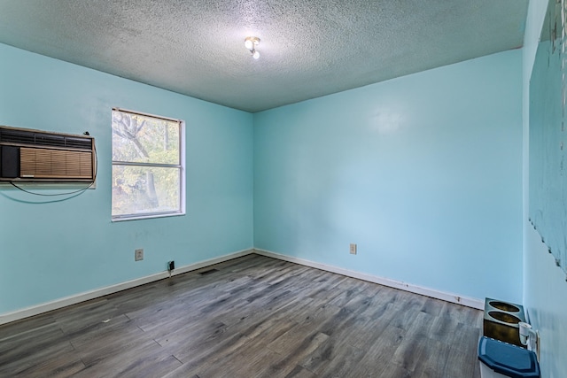 spare room with a textured ceiling, dark hardwood / wood-style floors, and an AC wall unit