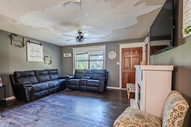 living room with a textured ceiling, dark hardwood / wood-style floors, and ceiling fan