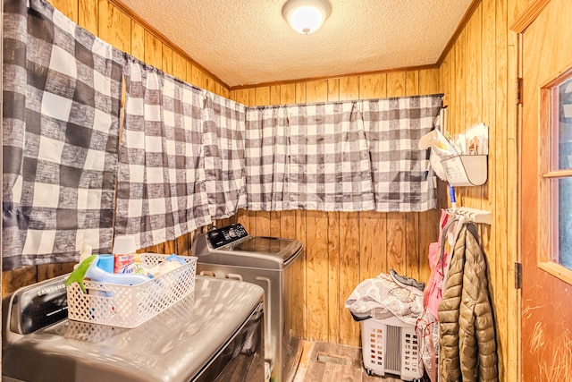 laundry room with a textured ceiling, wood walls, and washing machine and clothes dryer