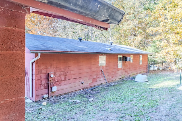 view of side of home with an AC wall unit and a yard