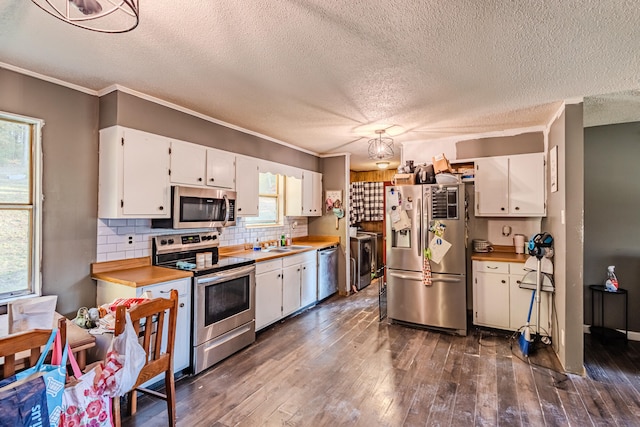 kitchen featuring stainless steel appliances, white cabinetry, dark hardwood / wood-style floors, and crown molding