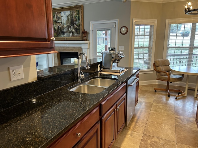 kitchen with dishwasher, a tile fireplace, sink, dark stone countertops, and a chandelier