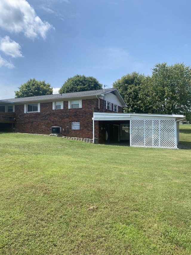 rear view of house featuring a lawn, central AC unit, and a carport