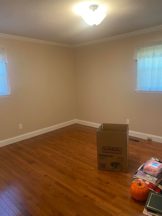 spare room featuring ornamental molding, a textured ceiling, and dark wood-type flooring