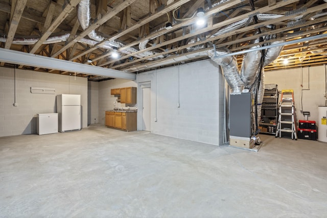 basement with water heater, white fridge, sink, and heating unit