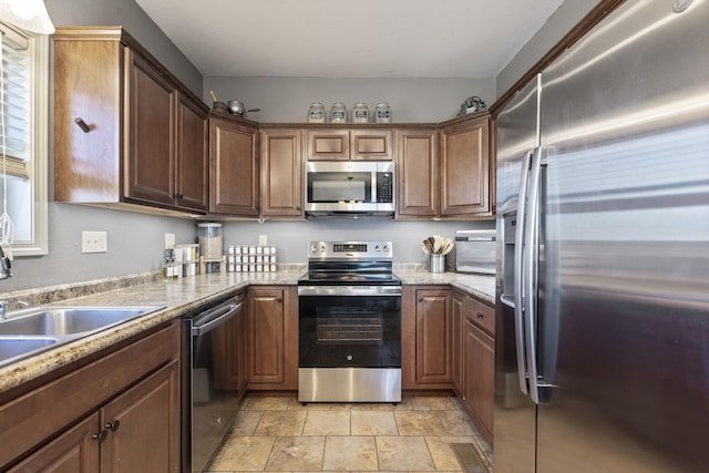 kitchen with light stone counters, appliances with stainless steel finishes, and sink