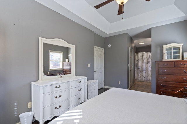 bedroom with ceiling fan, ensuite bathroom, a raised ceiling, and tile patterned flooring