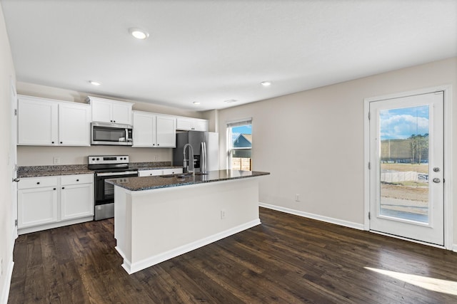 kitchen with a kitchen island with sink, dark hardwood / wood-style flooring, white cabinets, appliances with stainless steel finishes, and sink