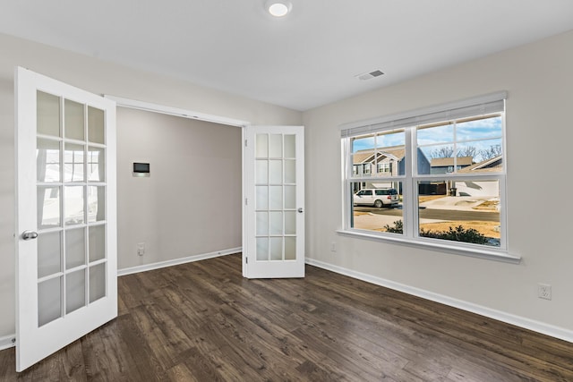 empty room featuring french doors and dark hardwood / wood-style flooring