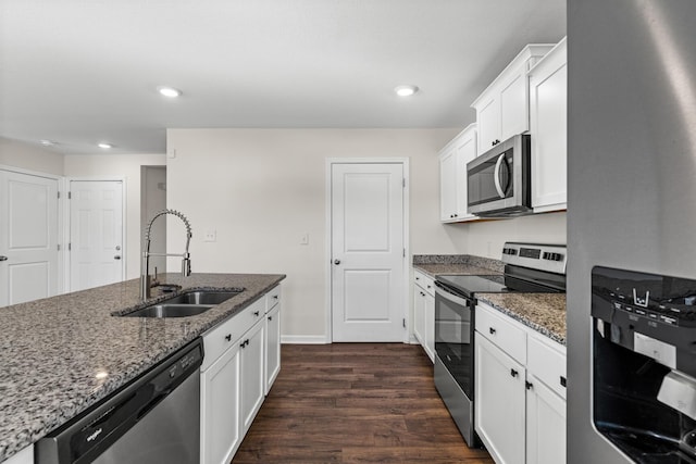 kitchen with white cabinets, appliances with stainless steel finishes, dark stone countertops, and sink