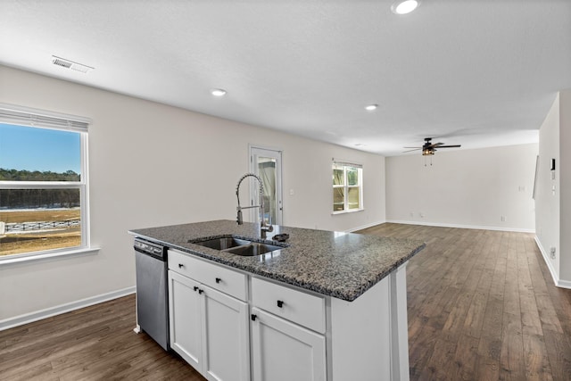 kitchen featuring dishwasher, a kitchen island with sink, dark stone counters, white cabinets, and sink