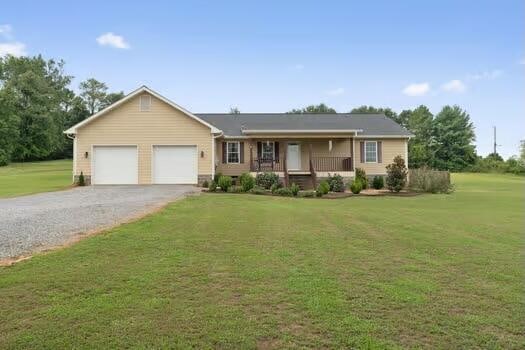 single story home featuring a porch, a garage, and a front lawn