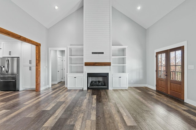 unfurnished living room featuring dark hardwood / wood-style flooring, a fireplace, high vaulted ceiling, and french doors