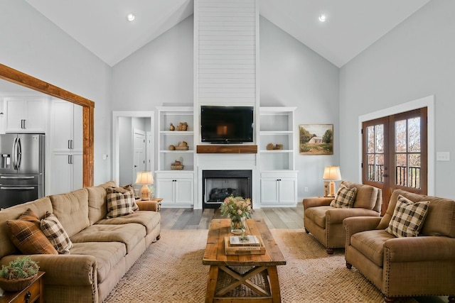 living room featuring french doors, a fireplace, high vaulted ceiling, and light hardwood / wood-style flooring