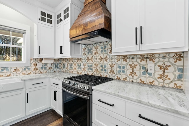 kitchen featuring white cabinets, custom range hood, black gas range oven, and light stone counters