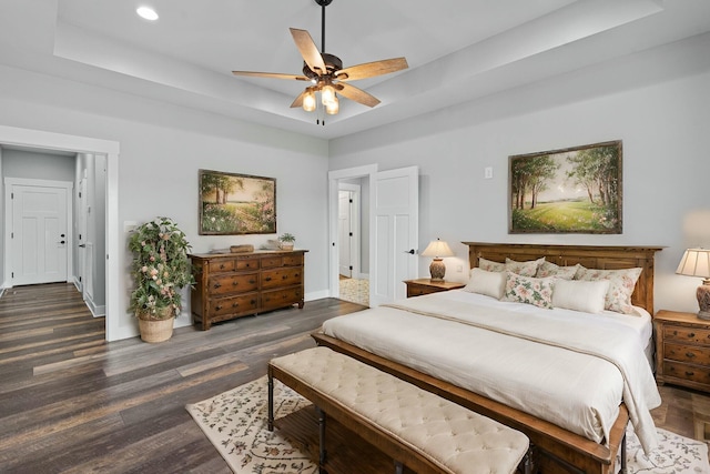 bedroom featuring dark hardwood / wood-style flooring, a raised ceiling, and ceiling fan