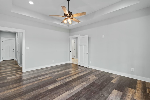 unfurnished room featuring dark hardwood / wood-style floors, ceiling fan, and a tray ceiling