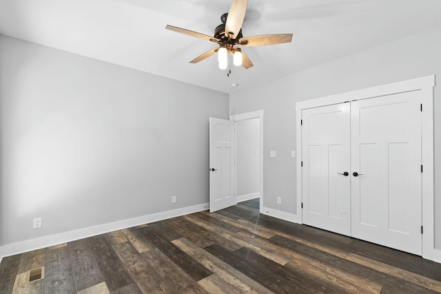 unfurnished bedroom with a closet, dark hardwood / wood-style floors, and ceiling fan