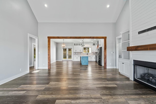 unfurnished living room featuring a fireplace, high vaulted ceiling, dark hardwood / wood-style floors, and sink