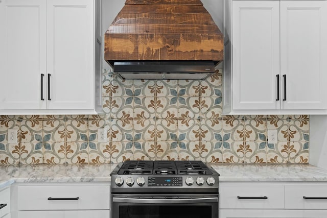 kitchen with stainless steel gas stove, light stone counters, white cabinetry, and backsplash