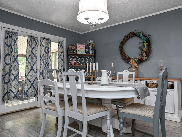 dining space featuring hardwood / wood-style floors, a textured ceiling, and crown molding