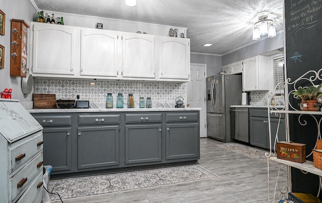 kitchen featuring ornamental molding, a textured ceiling, stainless steel appliances, gray cabinets, and white cabinetry