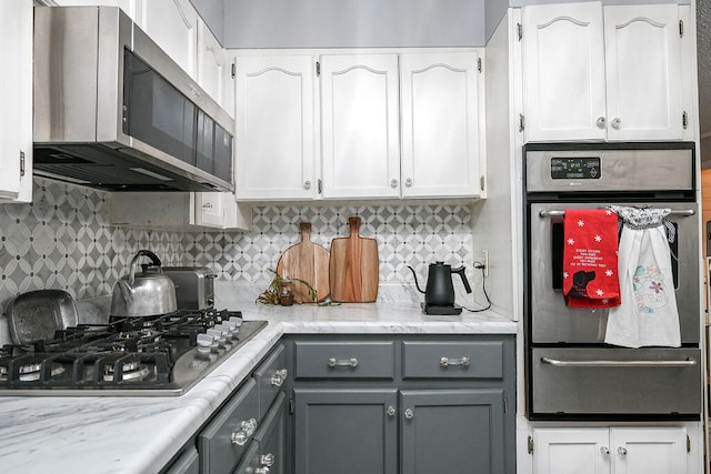 kitchen featuring tasteful backsplash, gray cabinets, white cabinets, and appliances with stainless steel finishes